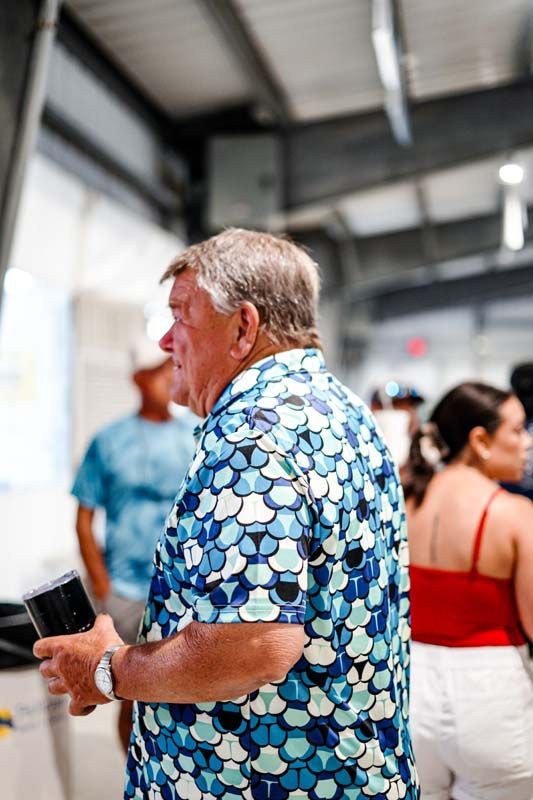 A man in a blue shirt is standing in a crowd of people.