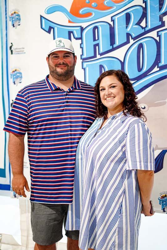 A man and a woman are standing next to each other in front of a sign.