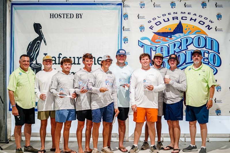 A group of men are posing for a picture in front of a banner.