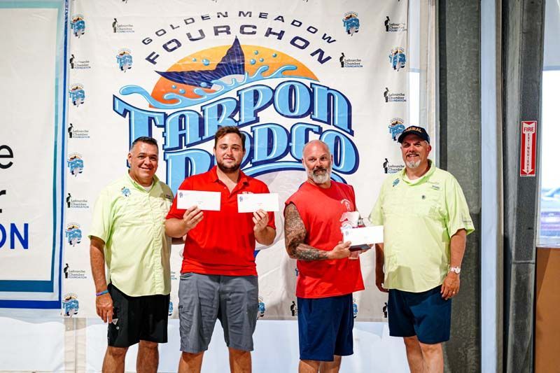 A group of men are standing next to each other in front of a sign that says tarpon rodeo.