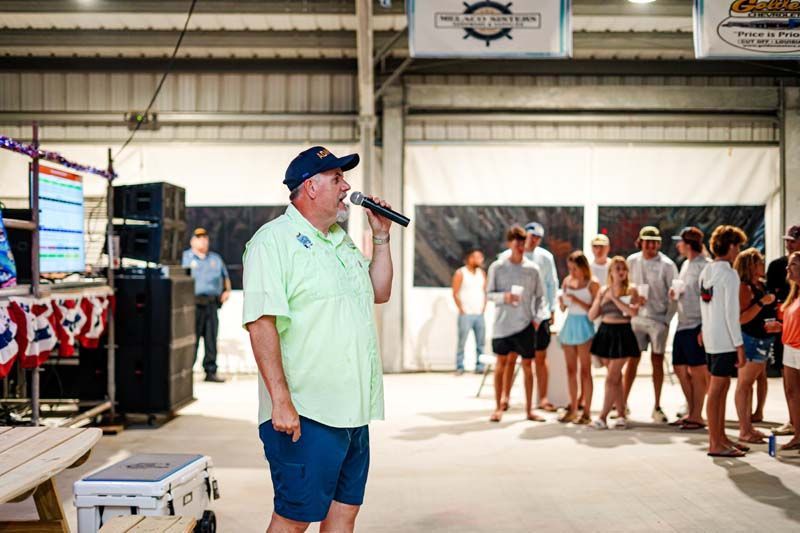 A man is standing in front of a group of people holding a microphone.