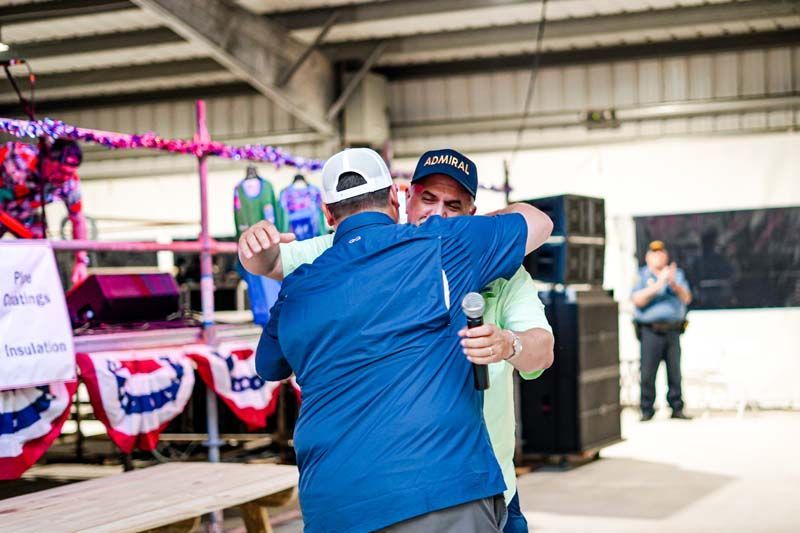 Two men are hugging each other in a room with a microphone.
