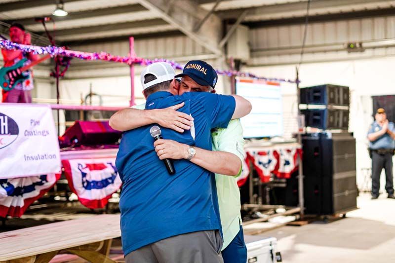 Two men are hugging each other in front of a microphone.