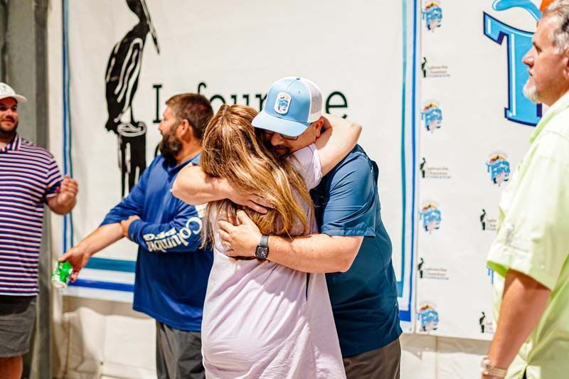 A group of people are hugging each other in front of a sign.