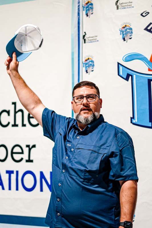 A man in a blue shirt is holding a hat in his hand.