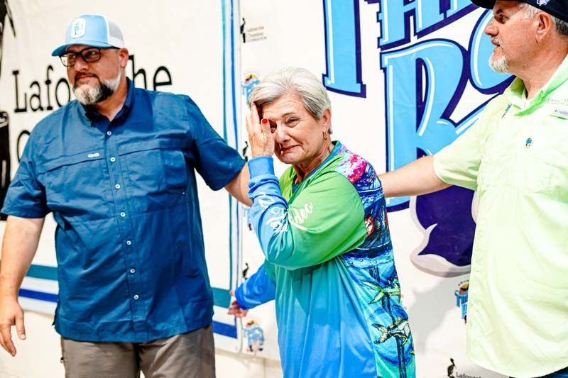 Two men and a woman are standing next to each other in front of a truck.