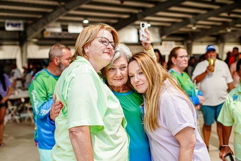 Three women are posing for a picture together at a party.