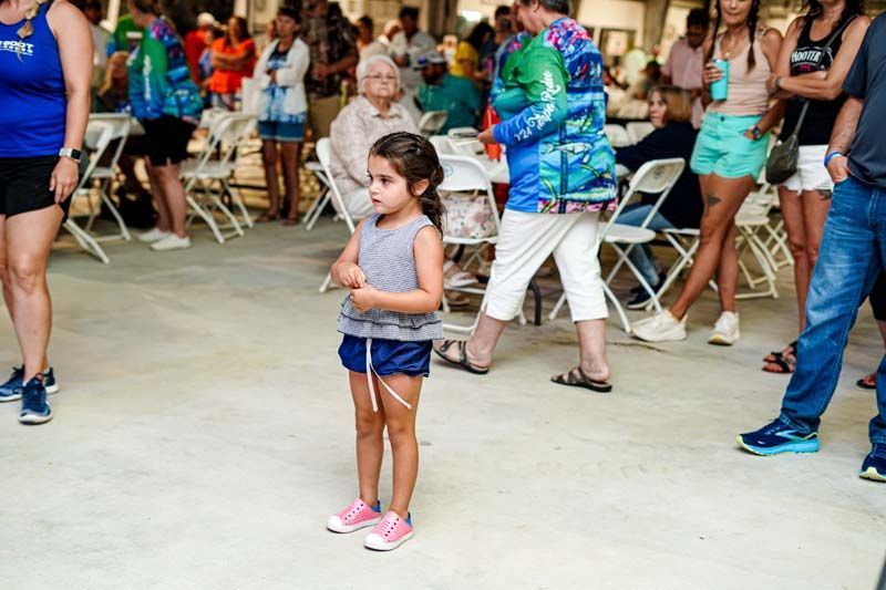 A little girl is standing in front of a crowd of people.