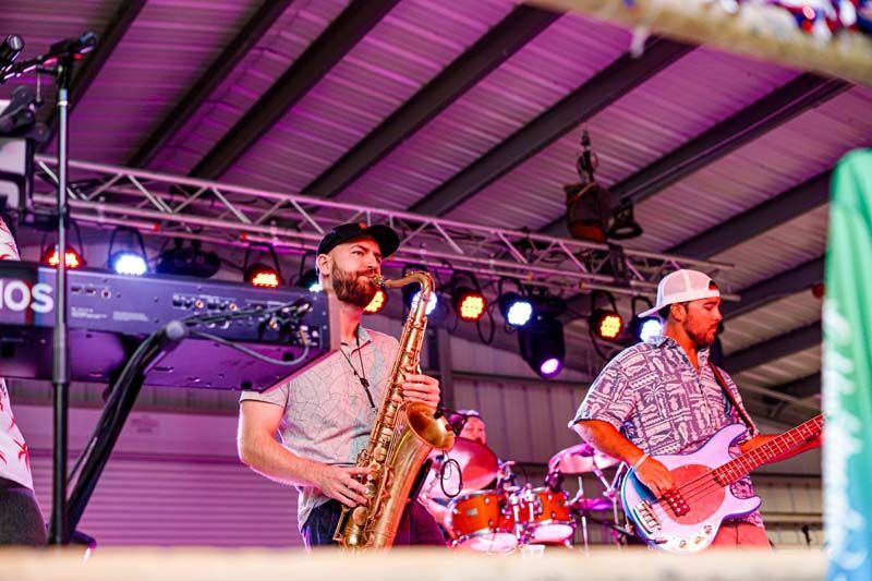 A man is playing a saxophone and a man is playing a guitar on stage.