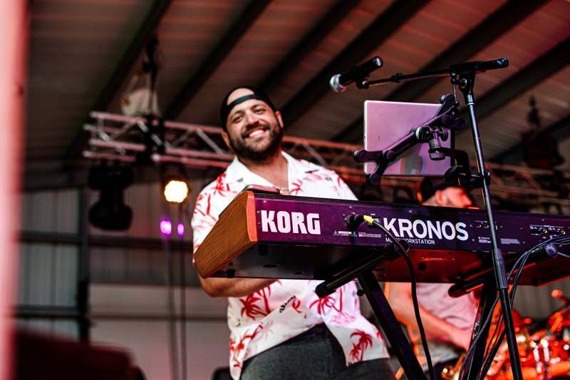 A man is playing a korg keyboard on a stage.