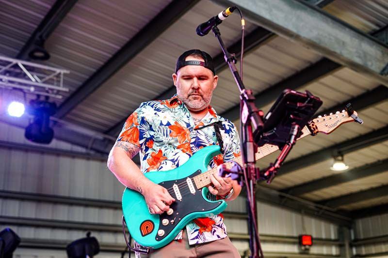 A man is playing a guitar on stage in front of a microphone.