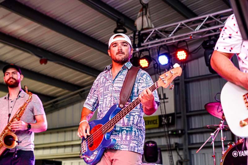 A man is playing a guitar on stage with a band.
