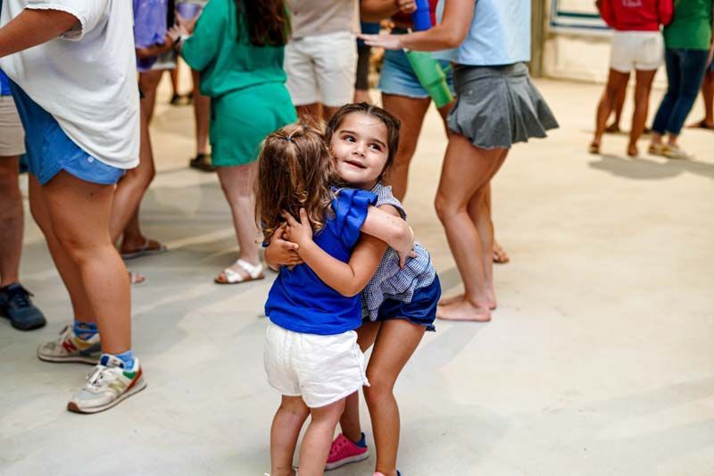 Two little girls are hugging each other in a crowd of people.