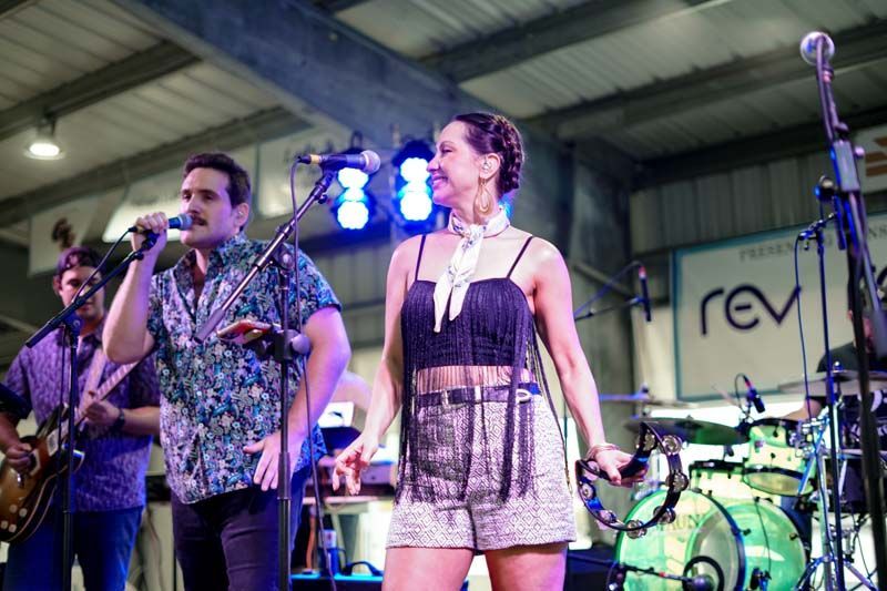 A man and a woman are singing into microphones on a stage.