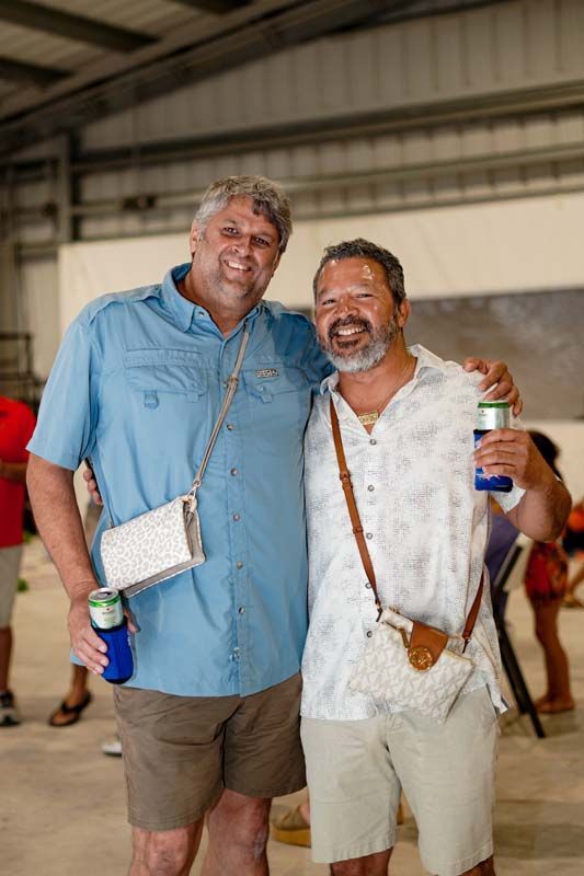 Two men are posing for a picture together while holding cans of beer.