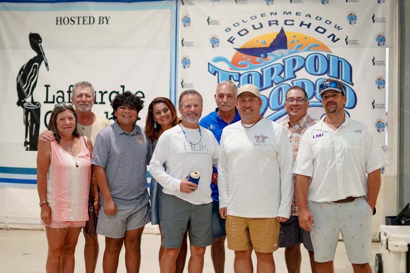 A group of people standing in front of a banner that says fourchon