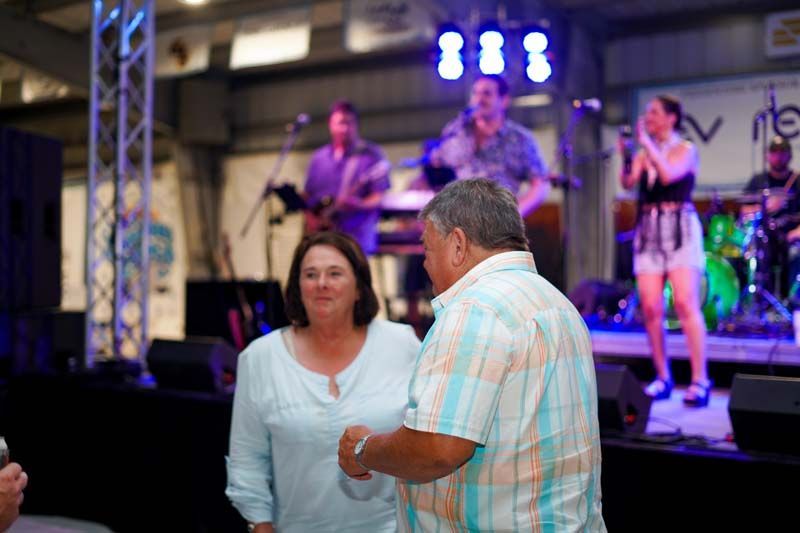 A man and a woman are dancing on a stage in front of a band.