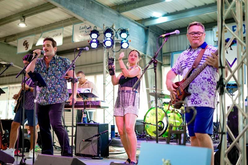 A group of people are standing on a stage playing instruments and singing into microphones.