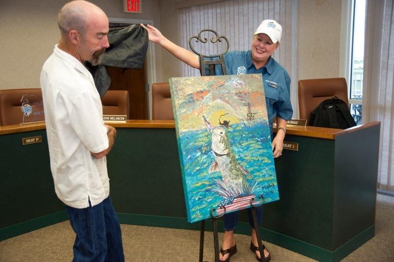 A man and a woman are looking at a painting of a dog in the ocean.
