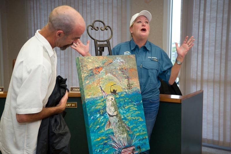 A man and a woman are looking at a painting of a fish in the ocean.