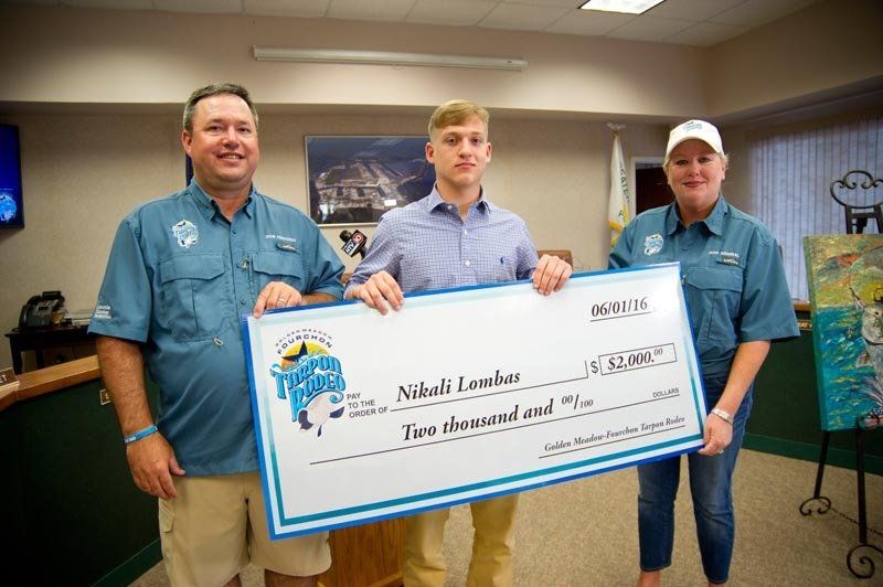 Three people are holding a large check in a room.