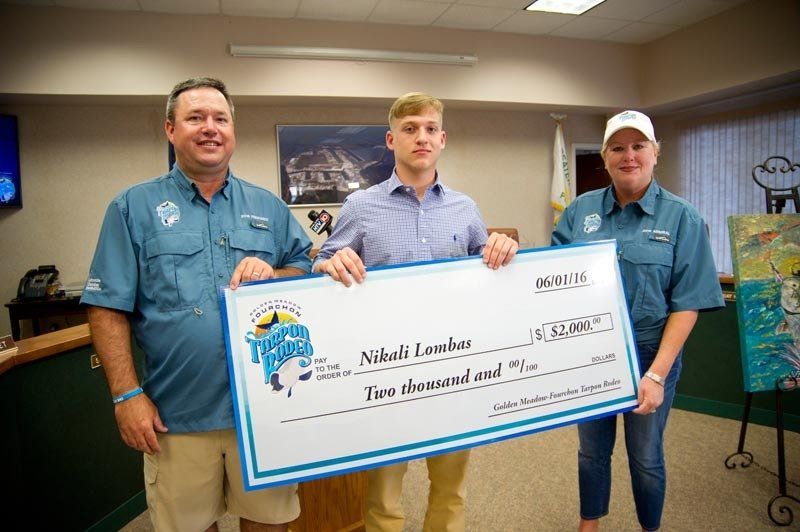 Three people are holding a large check in a room.