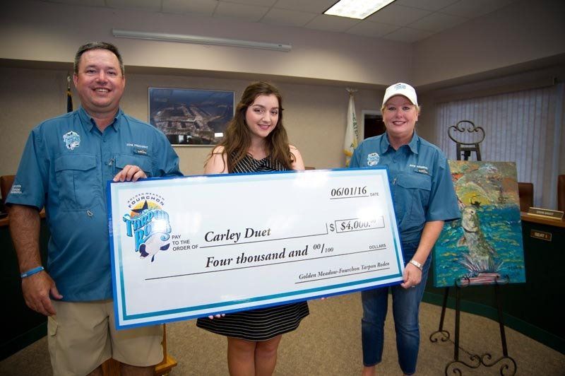 A woman is holding a large check in front of two men.