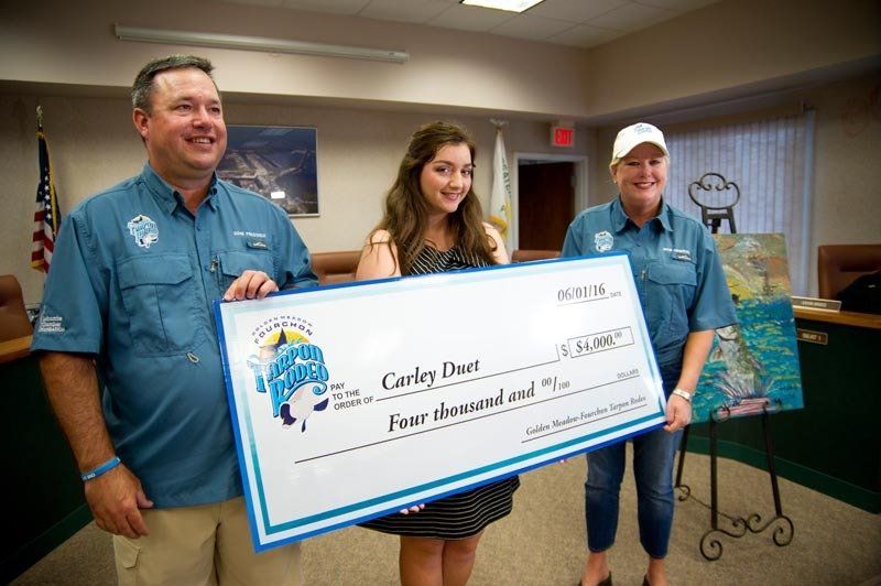 A man and two women are holding a large check in a room.