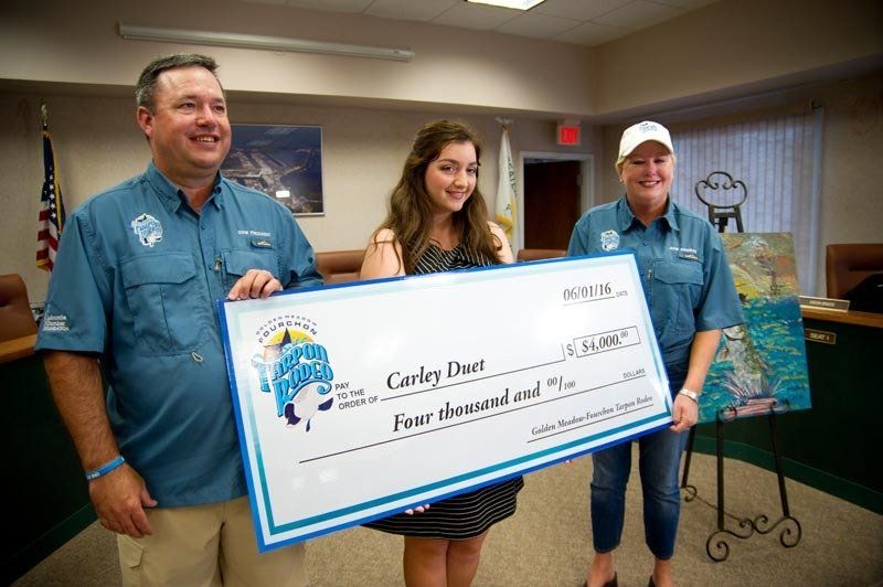 A man and two women are holding a large check in a room.