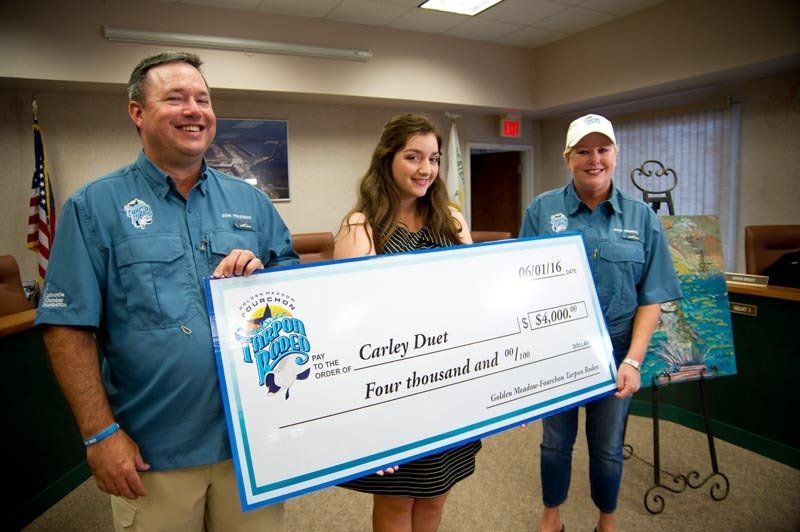 A man and two women are holding a large check.