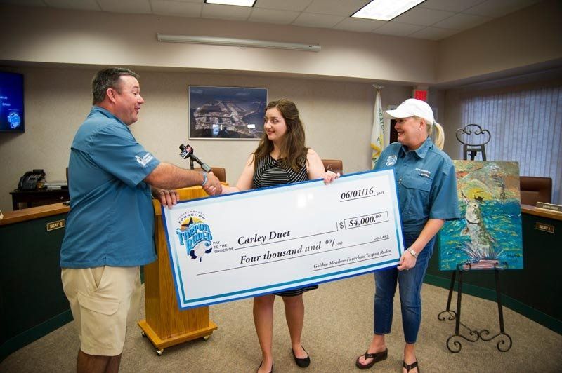 A man is shaking hands with a woman holding a large check.