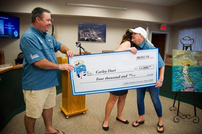 A man and a woman are holding a large check.