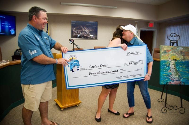 A man and woman are holding a large check in a room.