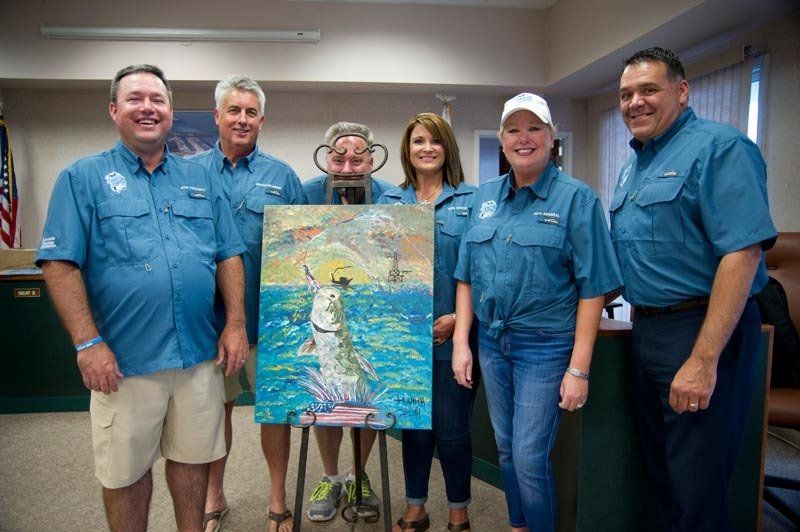 A group of people are standing around a painting of a fish in the ocean.