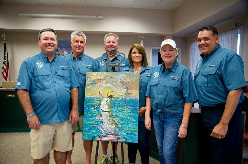 A group of people standing around a painting of a fish in the ocean.