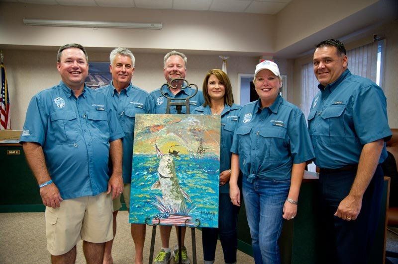 A group of people standing around a painting of a fish in the water.