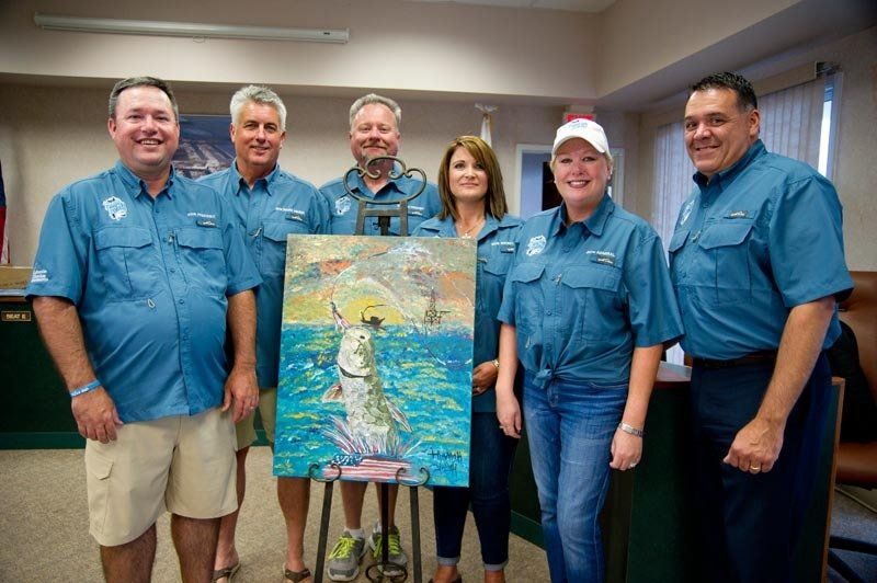 A group of people are standing around a painting of a fish.