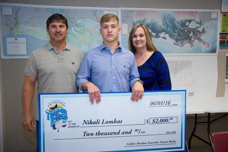 A man and woman are standing next to a young man holding a large check.