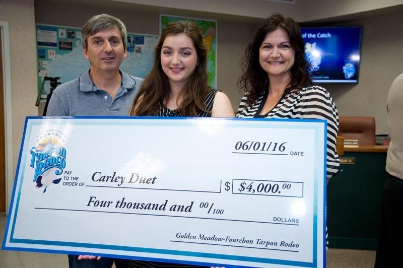 Three people holding a large check that says carley duet