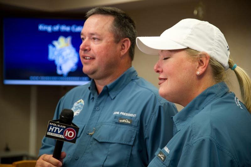 A man and a woman are standing next to each other and talking into a microphone.