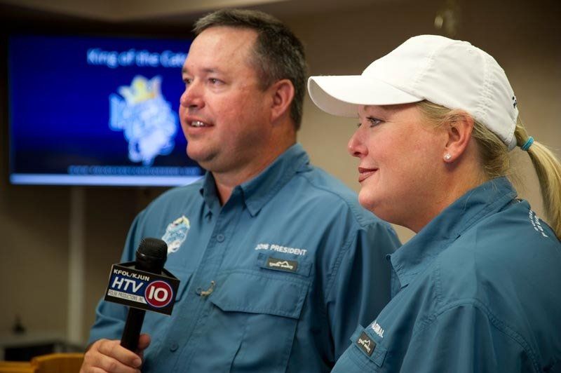 A man and a woman are standing next to each other and talking into a microphone.