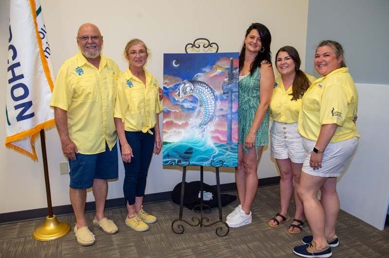 A group of people are posing for a picture in front of a painting.