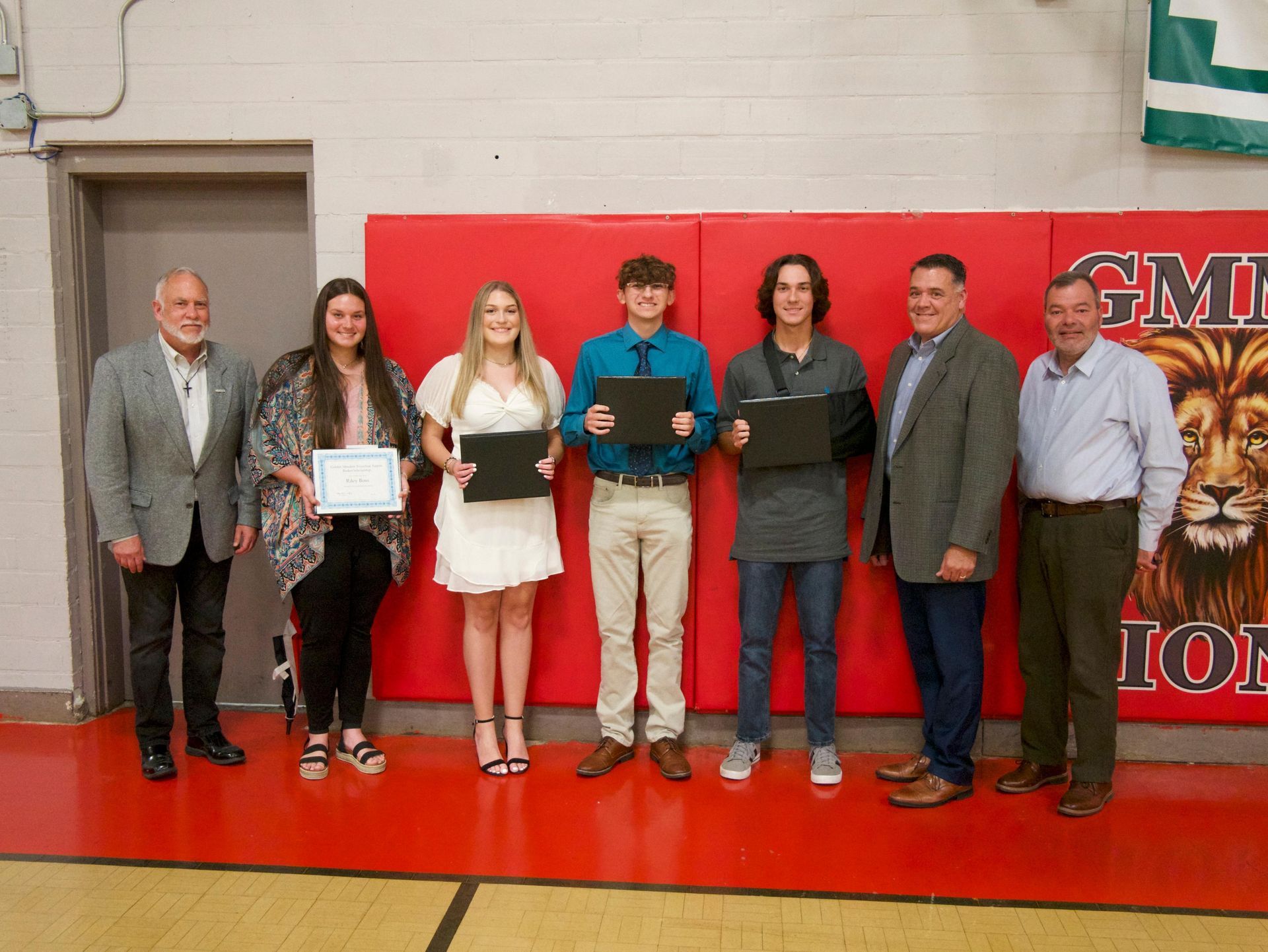 A group of people standing next to each other in a gym holding certificates.