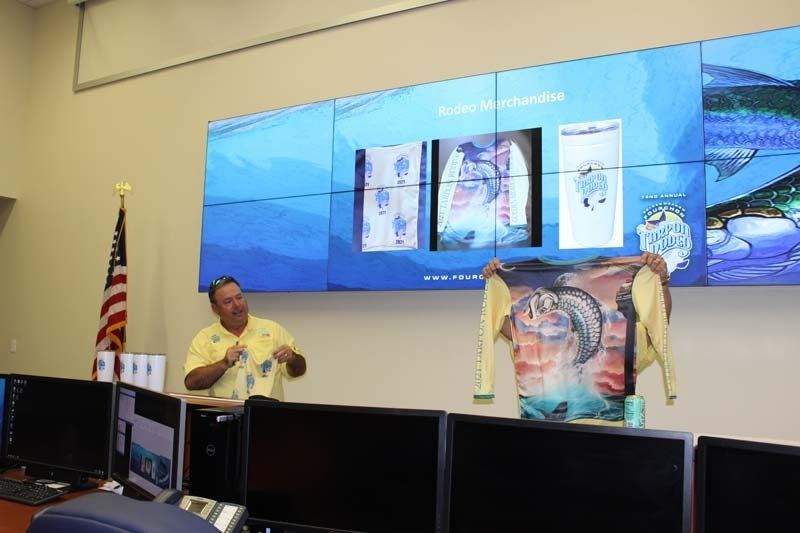 A man in a yellow shirt is standing in front of a large screen