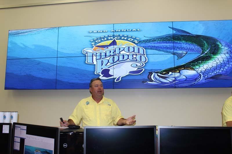 A man in a yellow shirt is standing in front of a screen that says florida rodeo