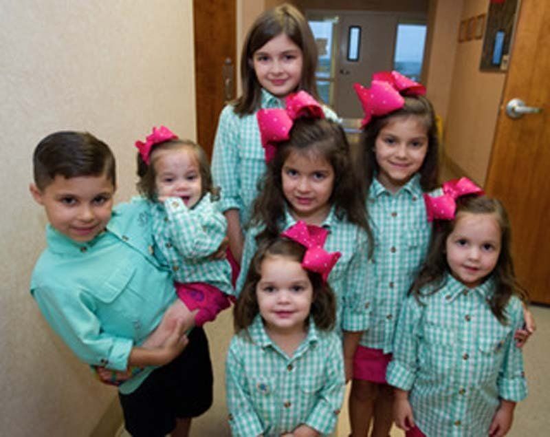 A group of children are posing for a picture in a hallway.
