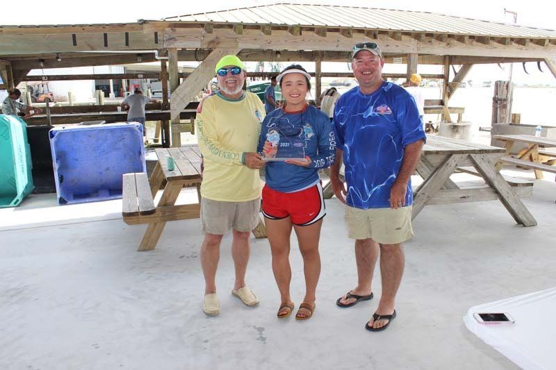 Three people standing next to each other in front of a picnic table