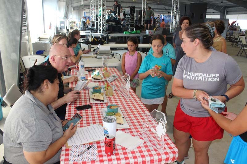 A woman wearing a herbalife nutrition shirt talks to a group of people