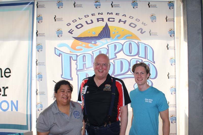 Three people standing in front of a sign that says fourchon