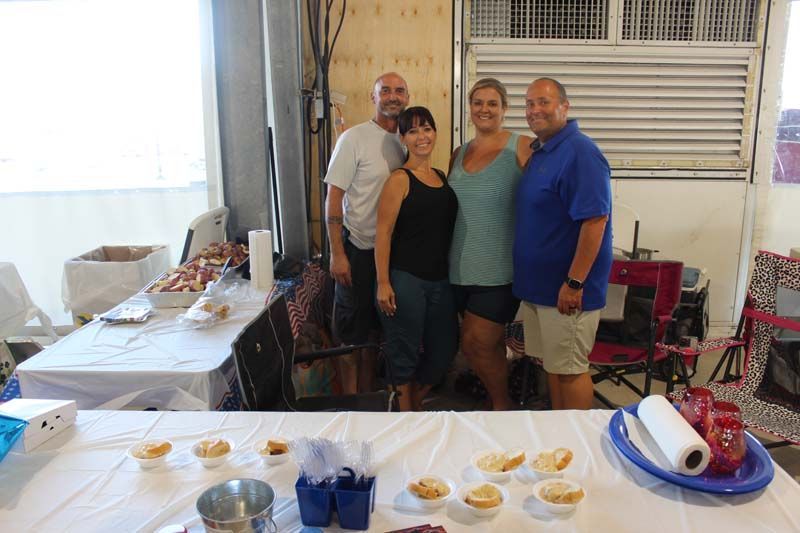 A group of people are posing for a picture in front of a table with food on it.